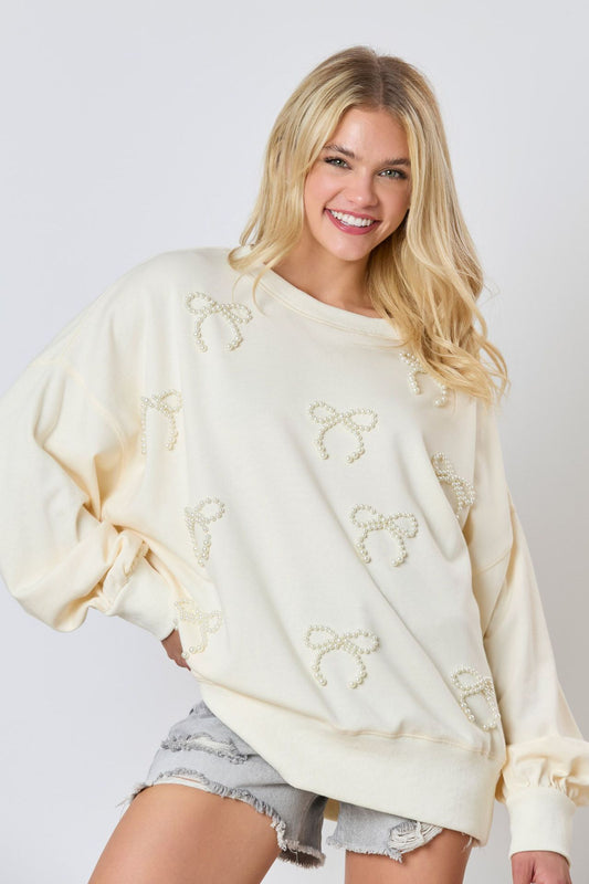 Vue rapprochée du nœud et des perles ornant le pull femme